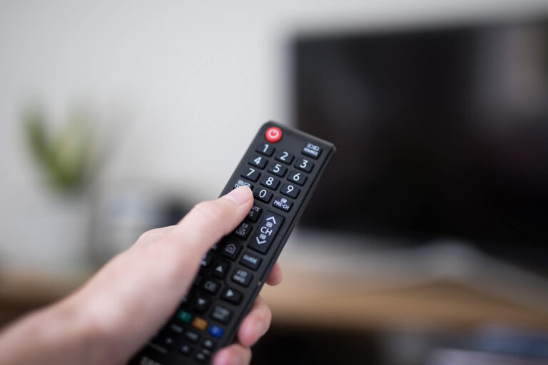 An individual holding a TV remote.